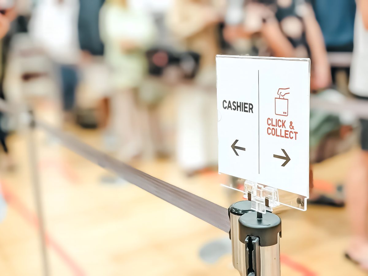 3. Queue stanchion and a CASHIER sign, people blurred out behind it.