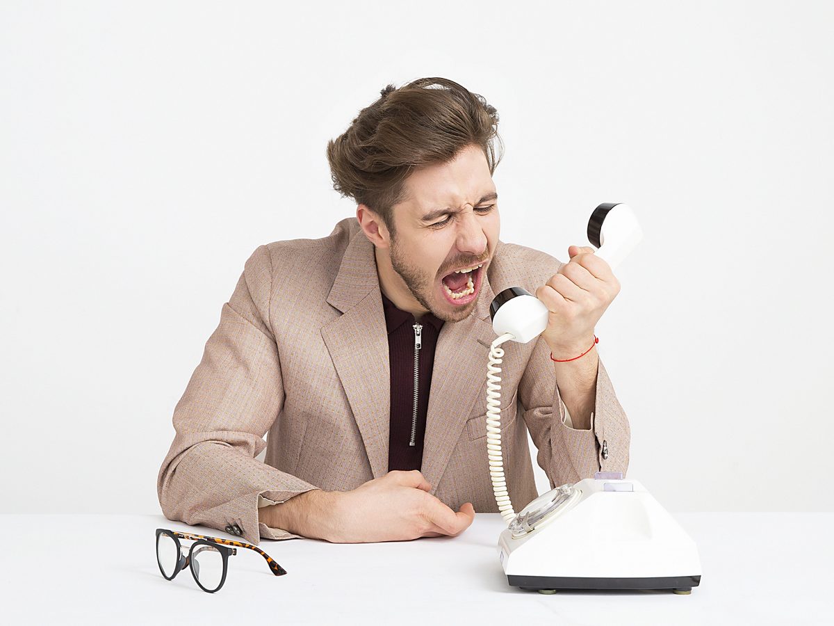 6. Studio shot, man shouting into a corded handset. Comedic — closest to John's tone.